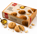 Box of Desi Ghee Nankhatai cookies with a bite taken out, surrounded by cookies and cashews on a white background.