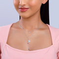 Woman wearing a silver necklace with a heart pendant on a light gray background